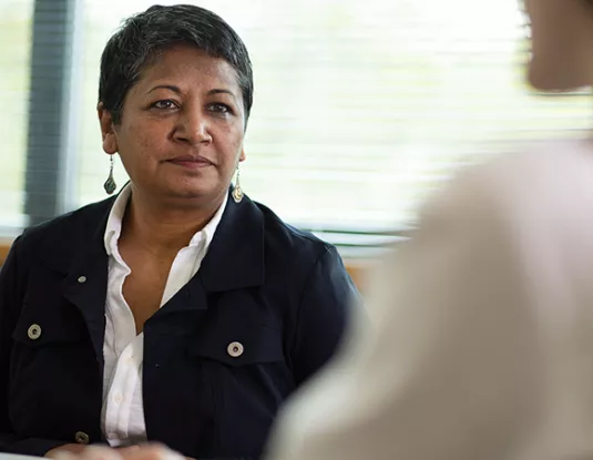 Asian woman sitting in an office opposite a colleague